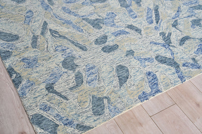 Blue-toned abstract rug with cream and beige stone-like shapes on light wood flooring.