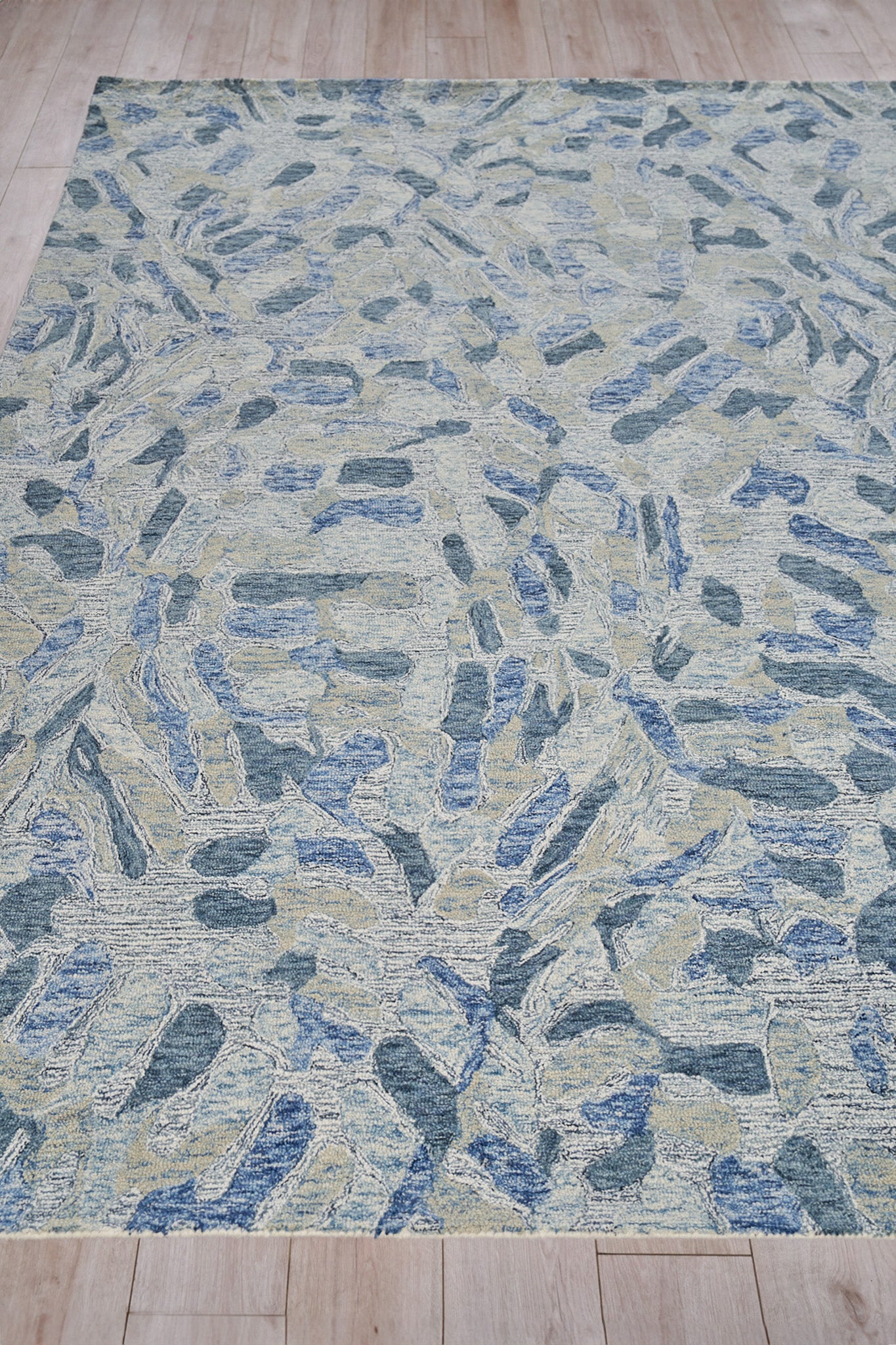 Blue, beige and gray abstract area rug with irregular stone-like shapes and a textured weave.