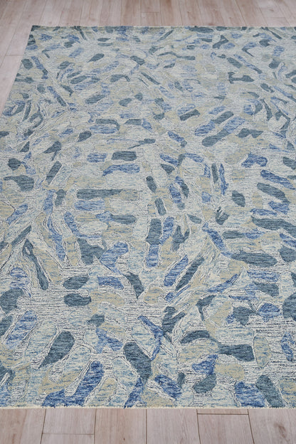 Blue, beige and gray abstract area rug with irregular stone-like shapes and a textured weave.