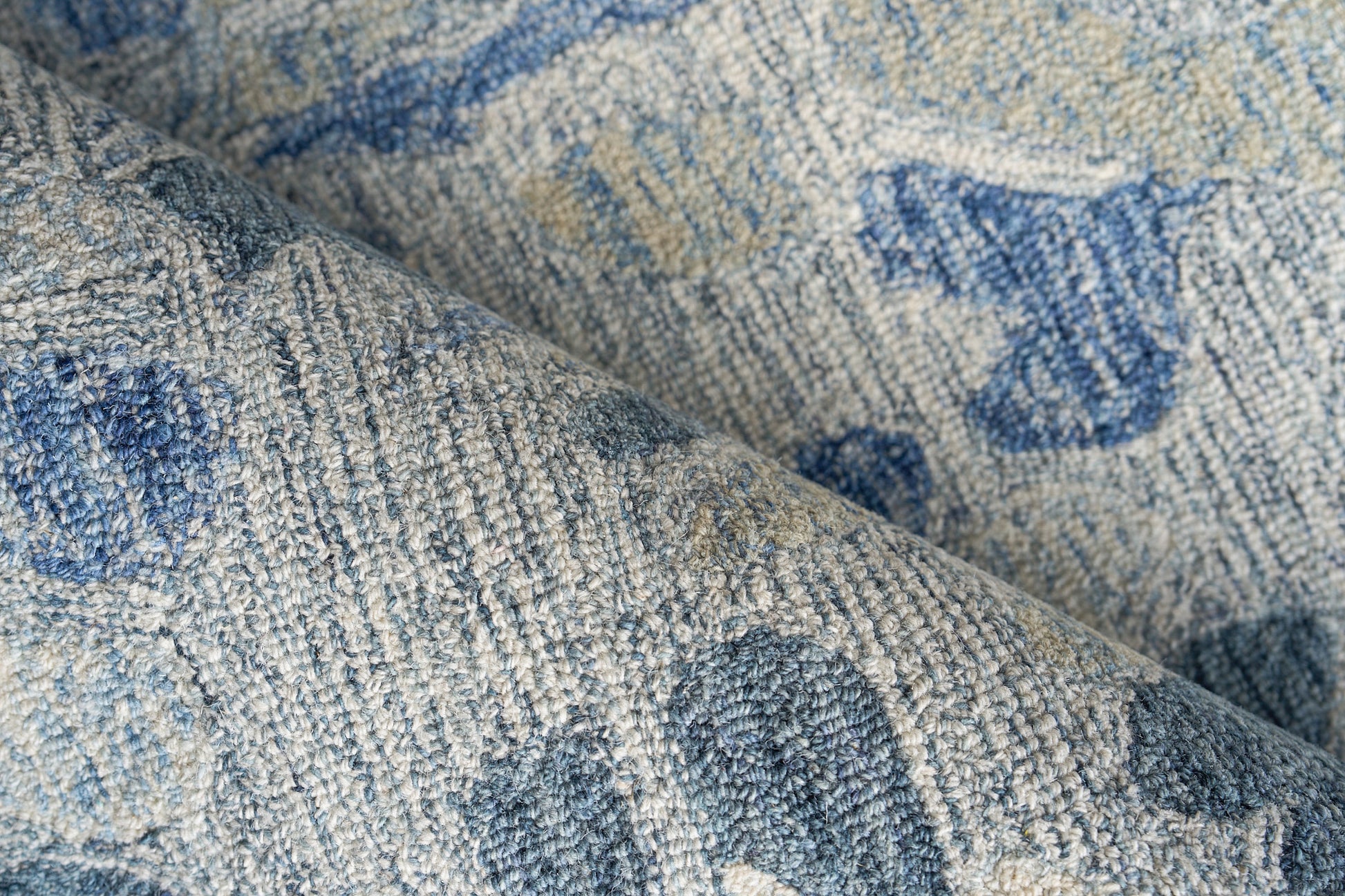 Blue and beige hand-tufted rug close-up, textured pile with an abstract distressed motif.