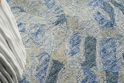 Blue and beige textured rug with abstract shapes; plush loop pile and a white pleated fabric edge visible.