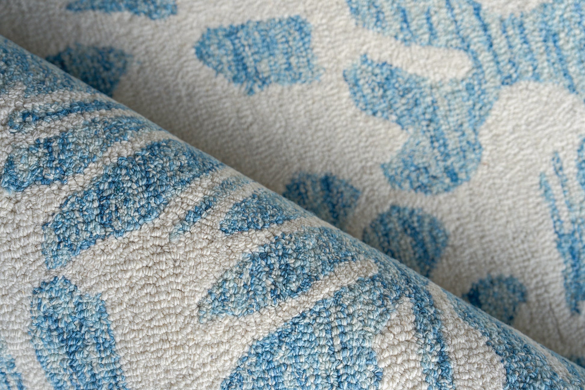 Beige rug with a light blue abstract pattern, plush hand-tufted texture, folded, 6' x 9'.