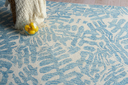 Blue and white abstract patterned rug with a clear glass pitcher of lemons and a cream chunky knit throw.