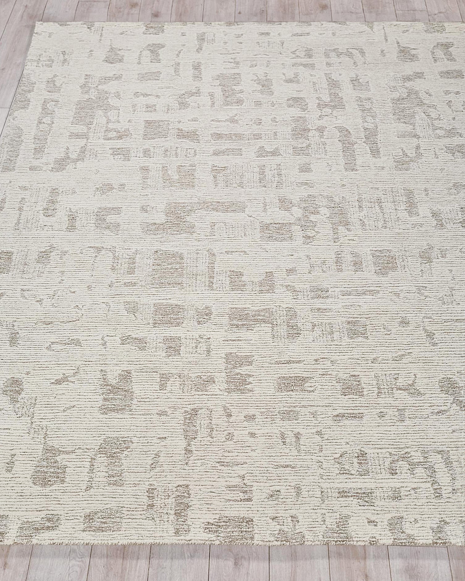 Beige area rug with abstract taupe pattern, textured loop pile, on light wood floor
