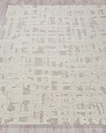 Beige area rug with abstract taupe pattern, textured loop pile, on light wood floor
