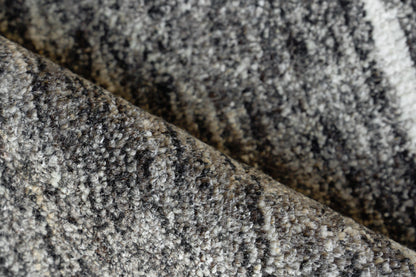 Close-up of a gray speckled rug with black, white and taupe hues; soft loop-pile texture.