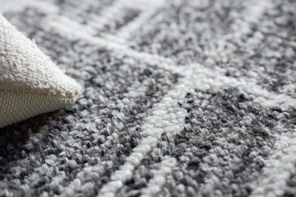 Close-up of a hand-knotted indoor rug in gray, black and ivory with a beige backing.