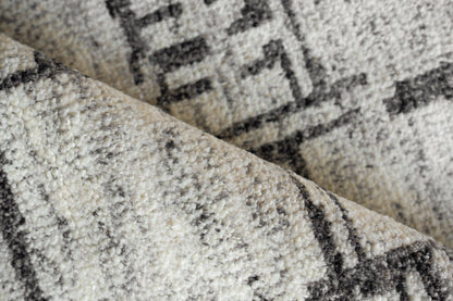 Beige cream rug with black geometric border, plush pile and folded edge detail.