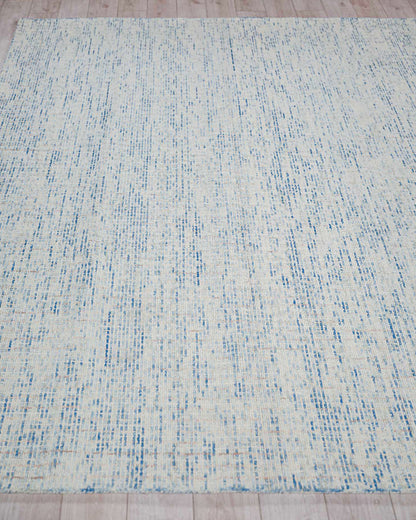 Rectangular blue and cream distressed area rug with vertical streak pattern on a light wood floor.