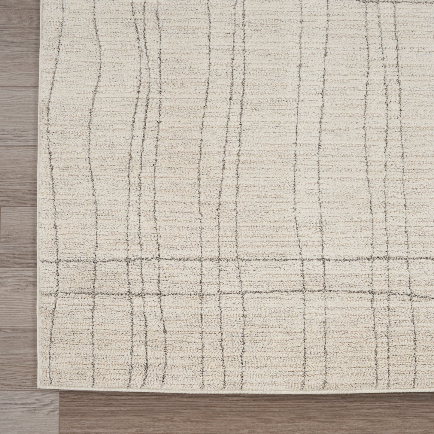 Beige area rug with subtle taupe grid lines, low-pile, on a wooden floor.