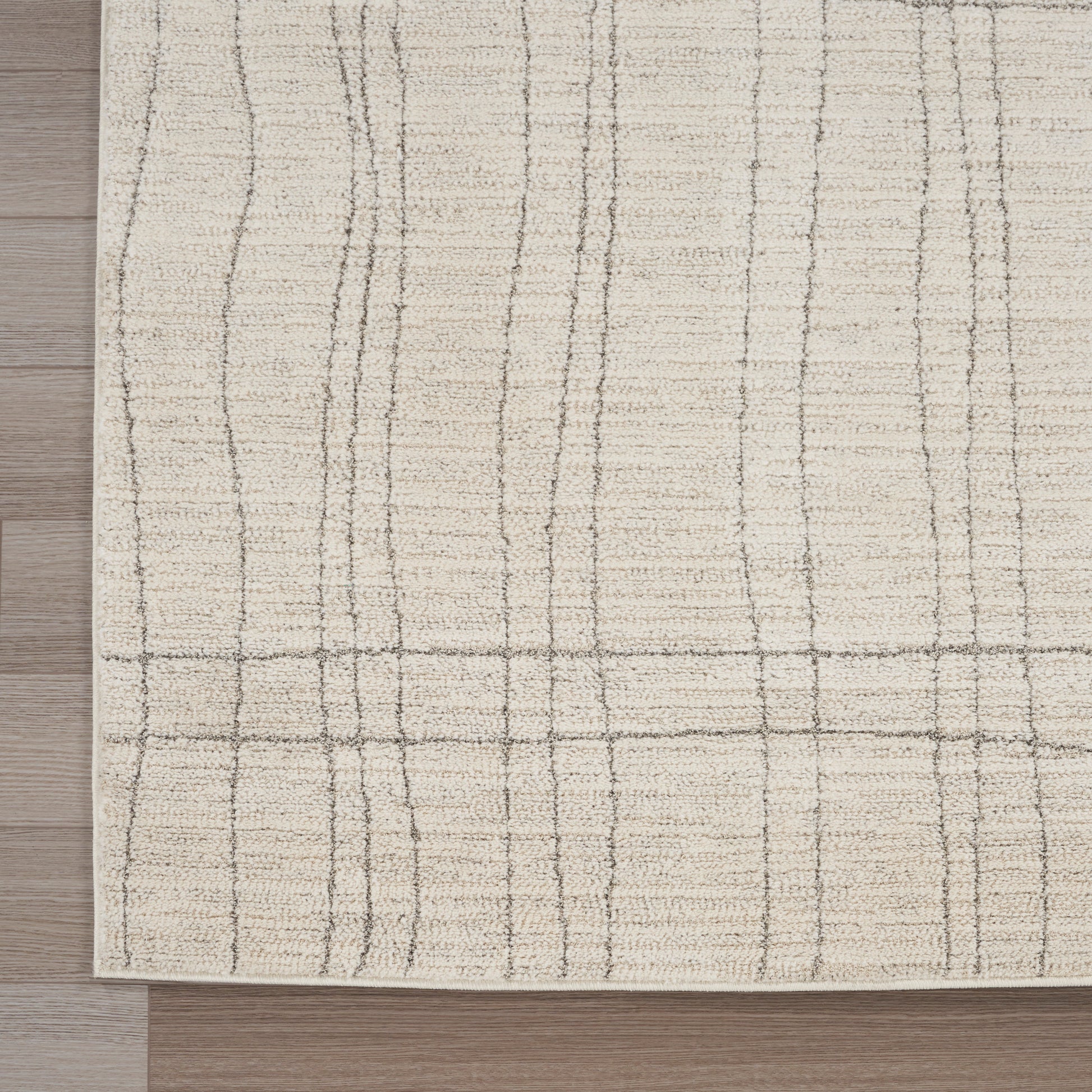 Beige area rug with subtle taupe grid lines, low-pile, on a wooden floor.
