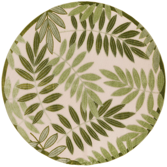Round ceramic plate with green palm frond leaf pattern on beige background.