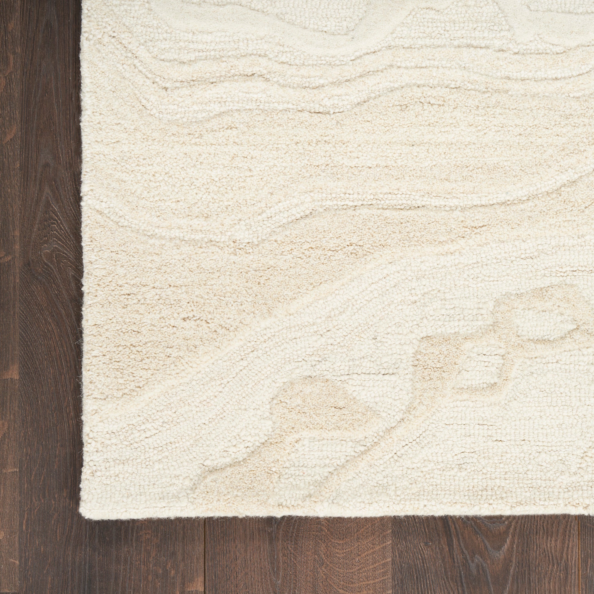 Cream textured area rug with subtle wavy pattern on dark wood floor.
