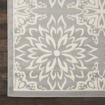 Gray woven area rug with a large white mandala floral motif and light border; farmhouse style living room rug.