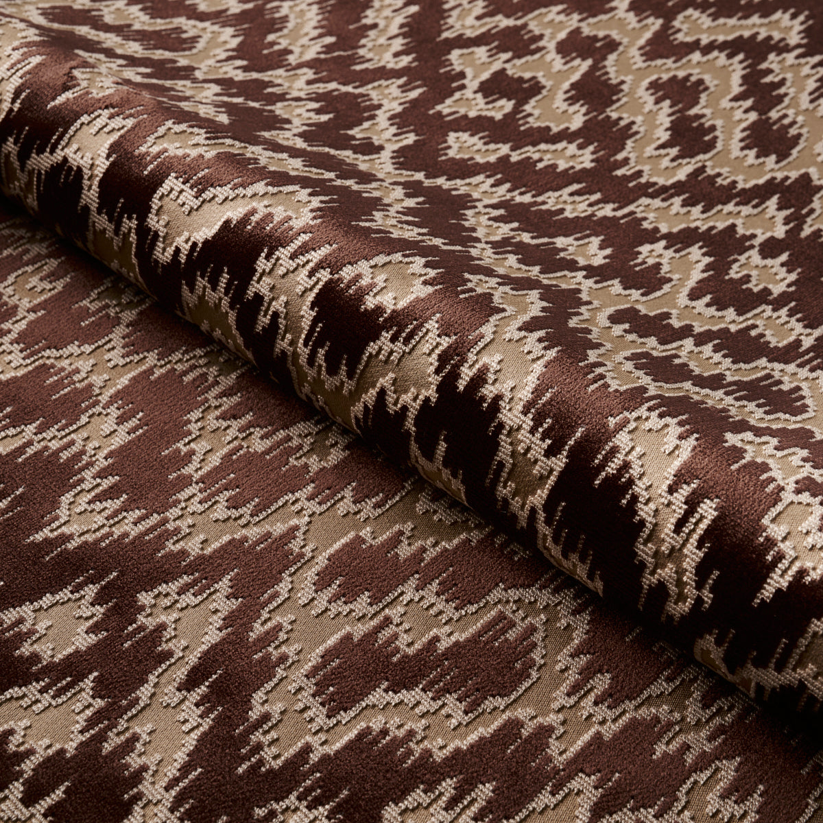 Brown and beige ikat-style geometric cut velvet fabric roll, suitable for upholstery.