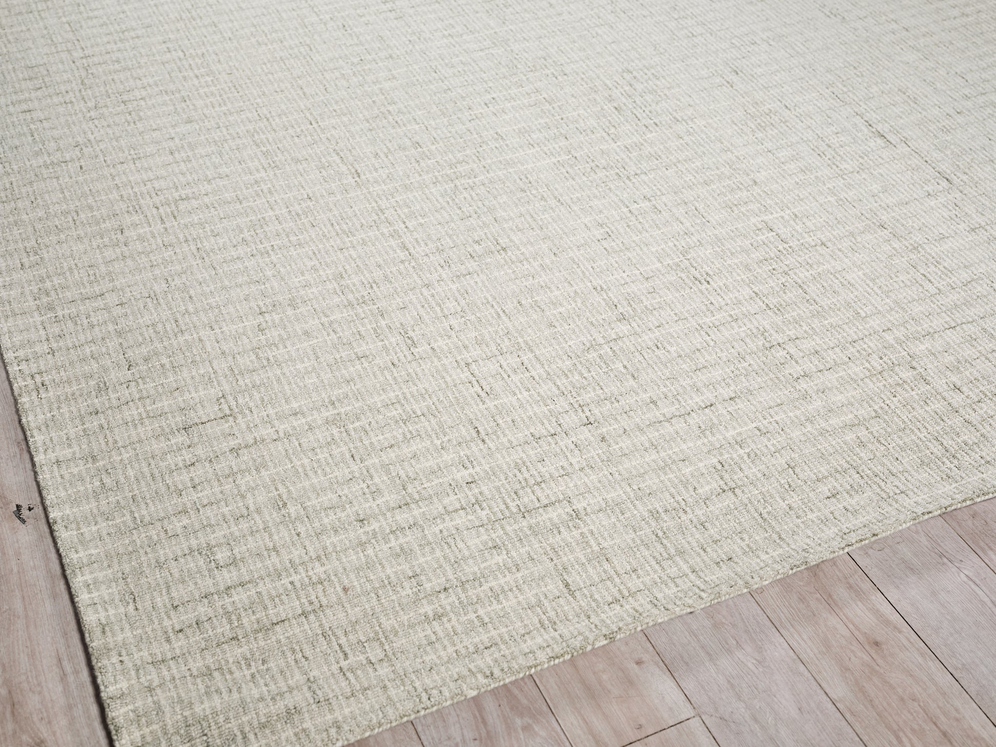 Neutral beige hand-tufted rug with a subtle grid texture on a light wood floor.