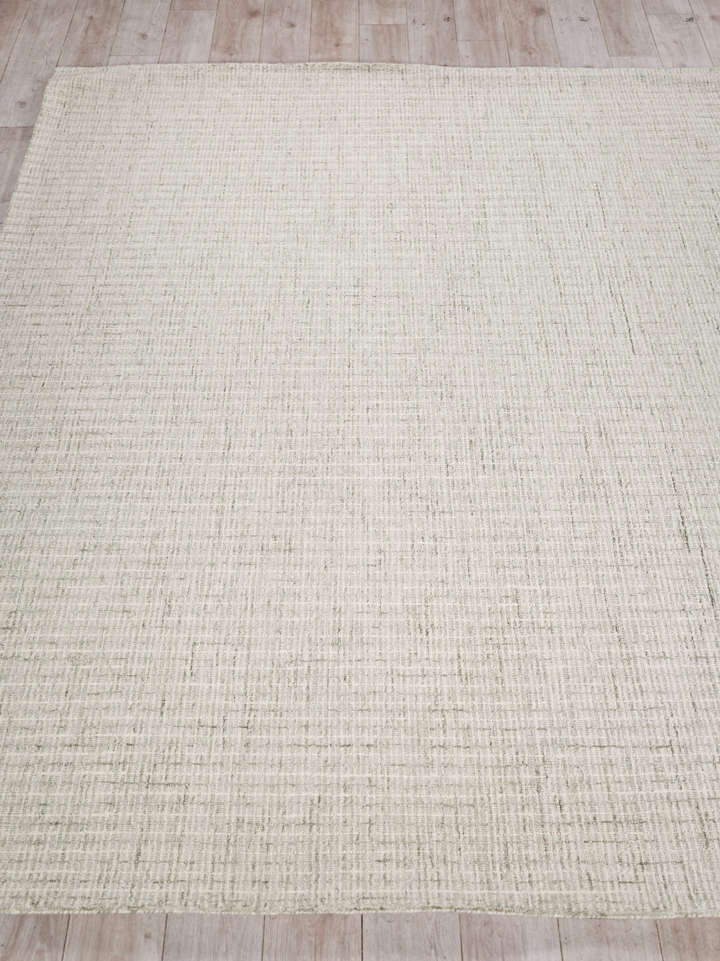 Rectangular beige hand tufted rug with a subtle grid texture on a light wooden floor.
