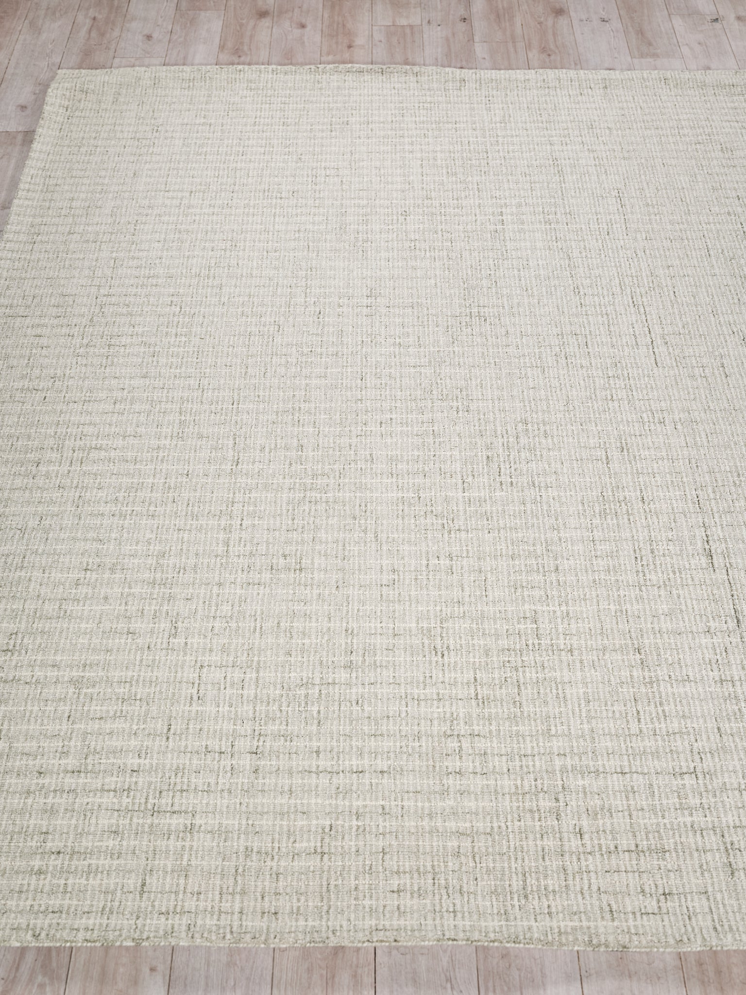 Rectangular beige hand tufted rug with a subtle grid texture on a light wooden floor.