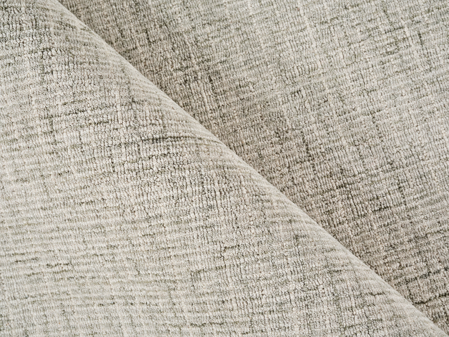 Beige textured woven rug, folded diagonally to show its soft, durable material.