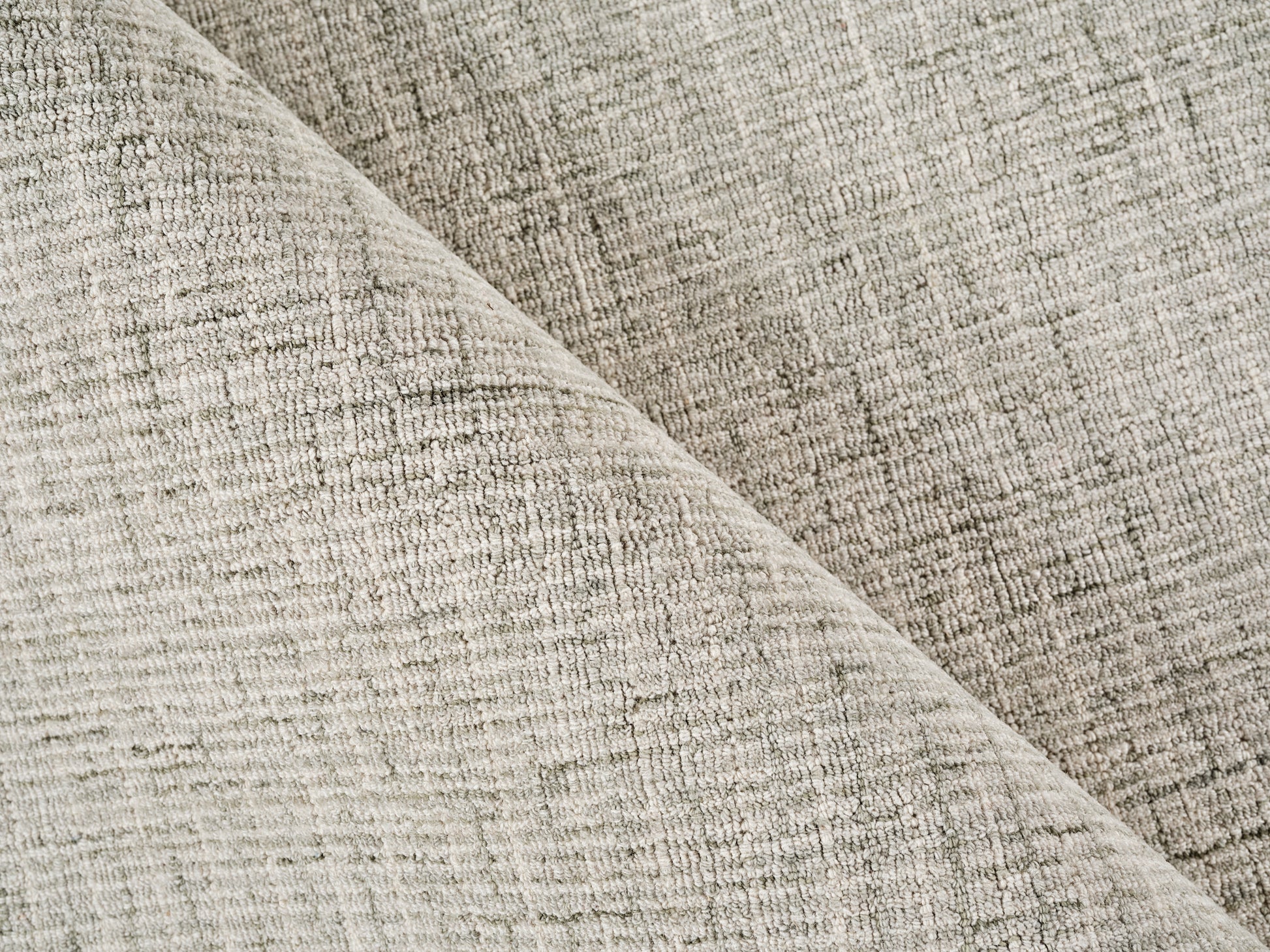 Beige textured woven rug, folded diagonally to show its soft, durable material.