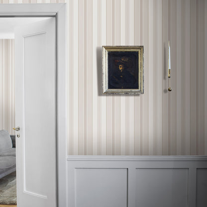 Beige vertical striped wallpaper with white wainscoting, silver-framed dark portrait, white door on the left, brass candle sconce.