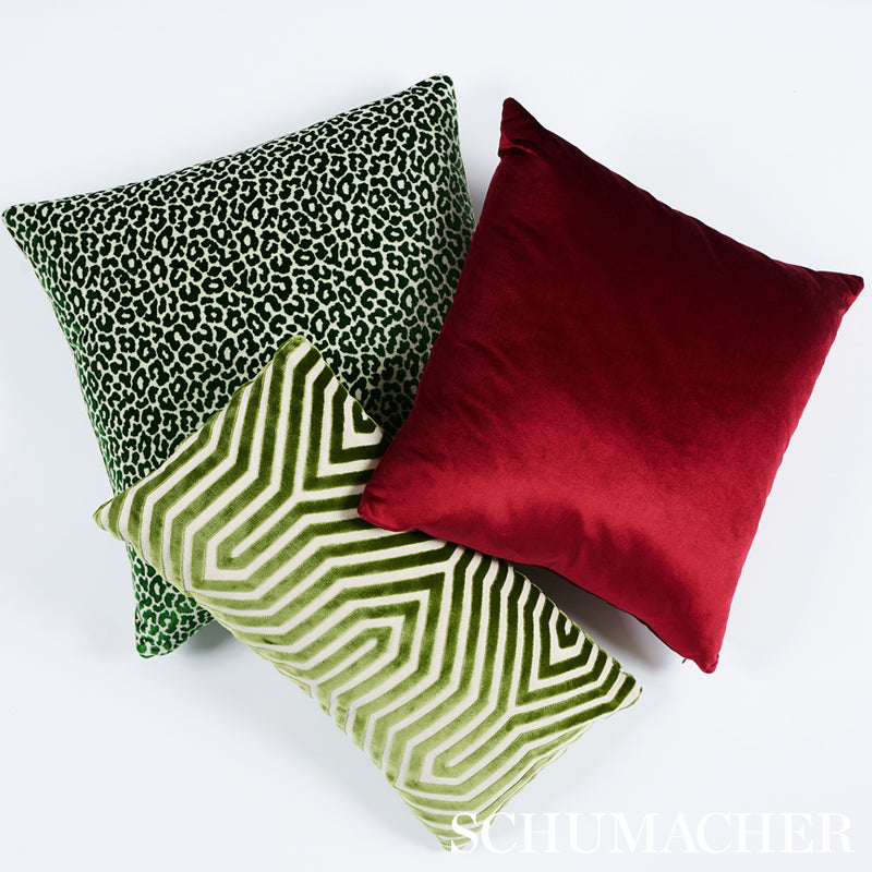 Three square decorative pillows: green leopard print, lime geometric pattern, and solid red velvet.