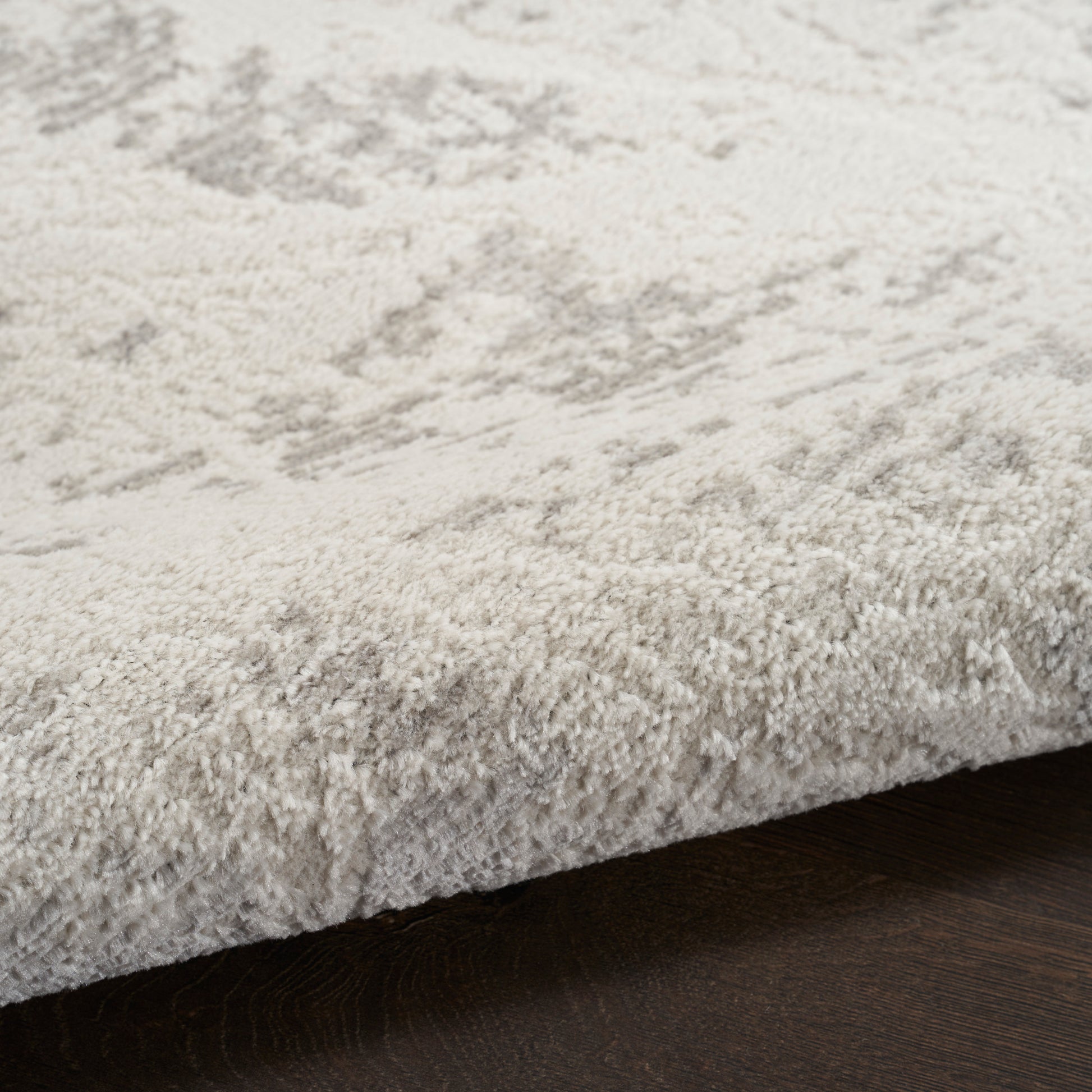 Cream shag rug with a subtle gray pattern and plush pile, rectangular shape on dark wood flooring.