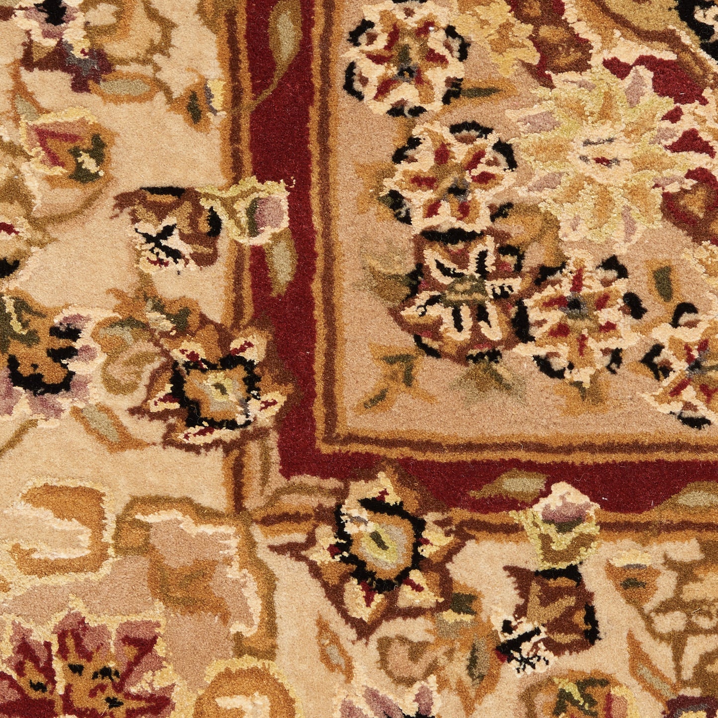 Close-up of a beige floral area rug with cream, tan and maroon motifs and a maroon border.