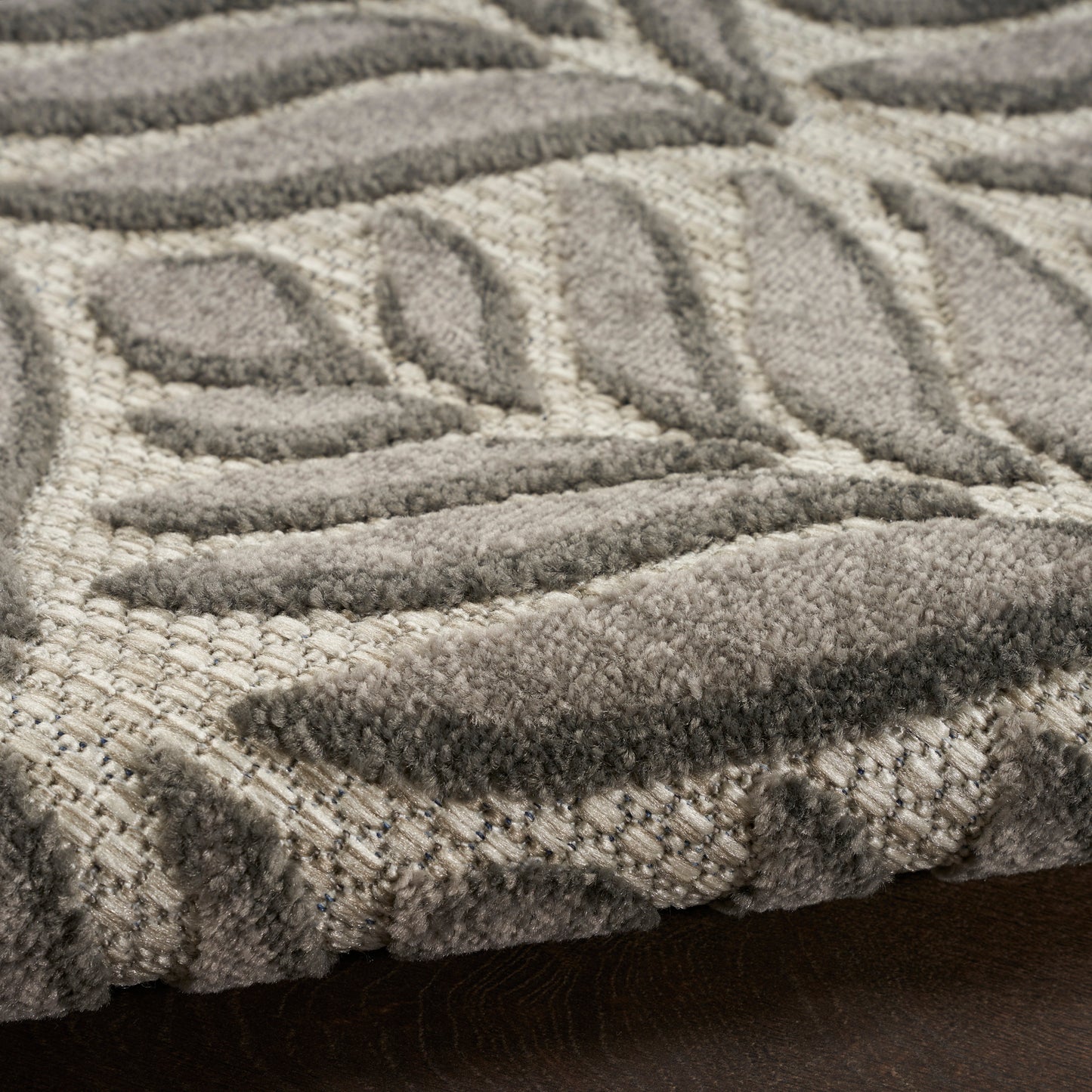 Beige and gray geometric patterned area rug with plush raised pile and leaf-like motifs.