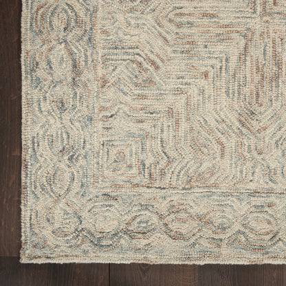 Shaggy-textured area rug in cream and pale blue with geometric square motifs and scrolling border on dark wood floor.