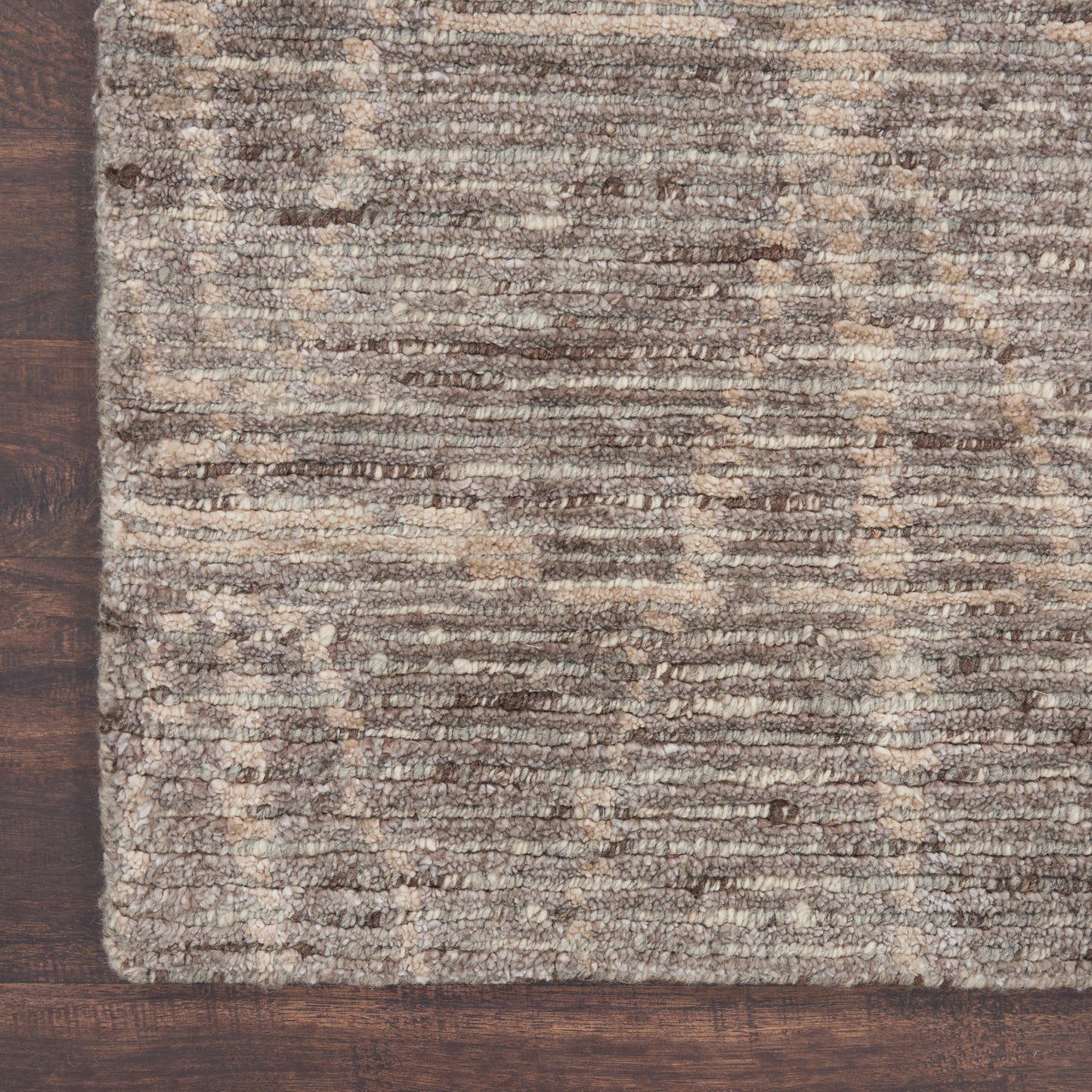 Brown and beige textured rug with subtle stripe pattern on dark wooden floor.
