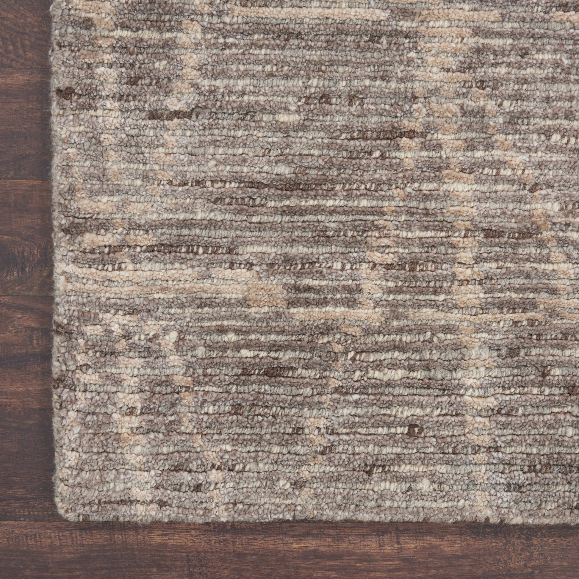 Brown and beige textured rug with subtle stripe pattern on dark wooden floor.