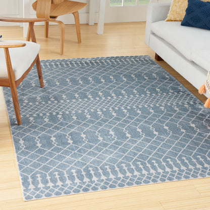 Blue-gray area rug with white geometric trellis pattern in a modern living room.