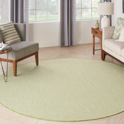 Round light-green textured area rug on a light wood floor, with gray and beige sofas and wooden side tables.