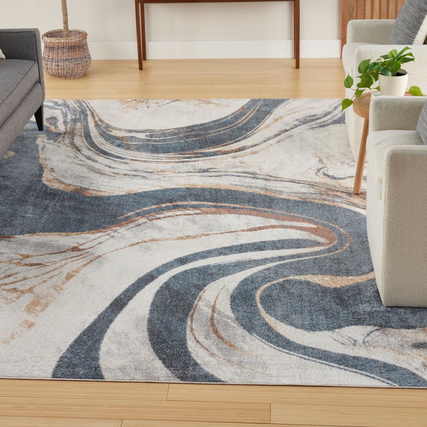 Abstract swirl area rug in navy blue, beige and cream with tan accents on light wood living room floor.