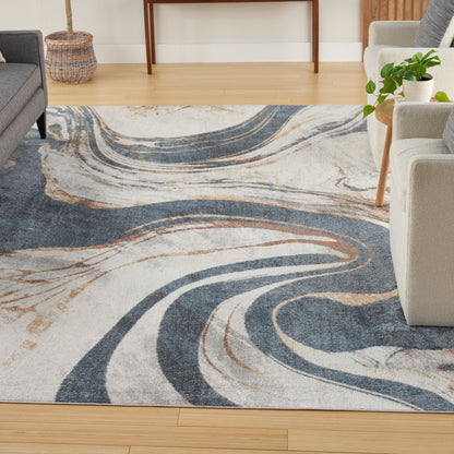 Abstract swirl area rug in navy blue, beige and cream with tan accents on light wood living room floor.