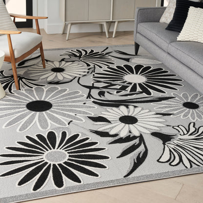 Light gray area rug (7' x 10') with woven texture in a modern living room with a gray sofa.