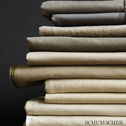 Stack of neutral chenille fabrics in greige tones (beige, taupe, cream), folded with varied textures against a dark background.