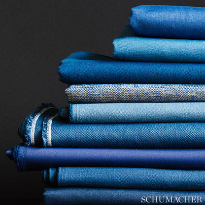 Stack of blue fabrics in varied shades and textures, denim-like, linen, against a dark background.