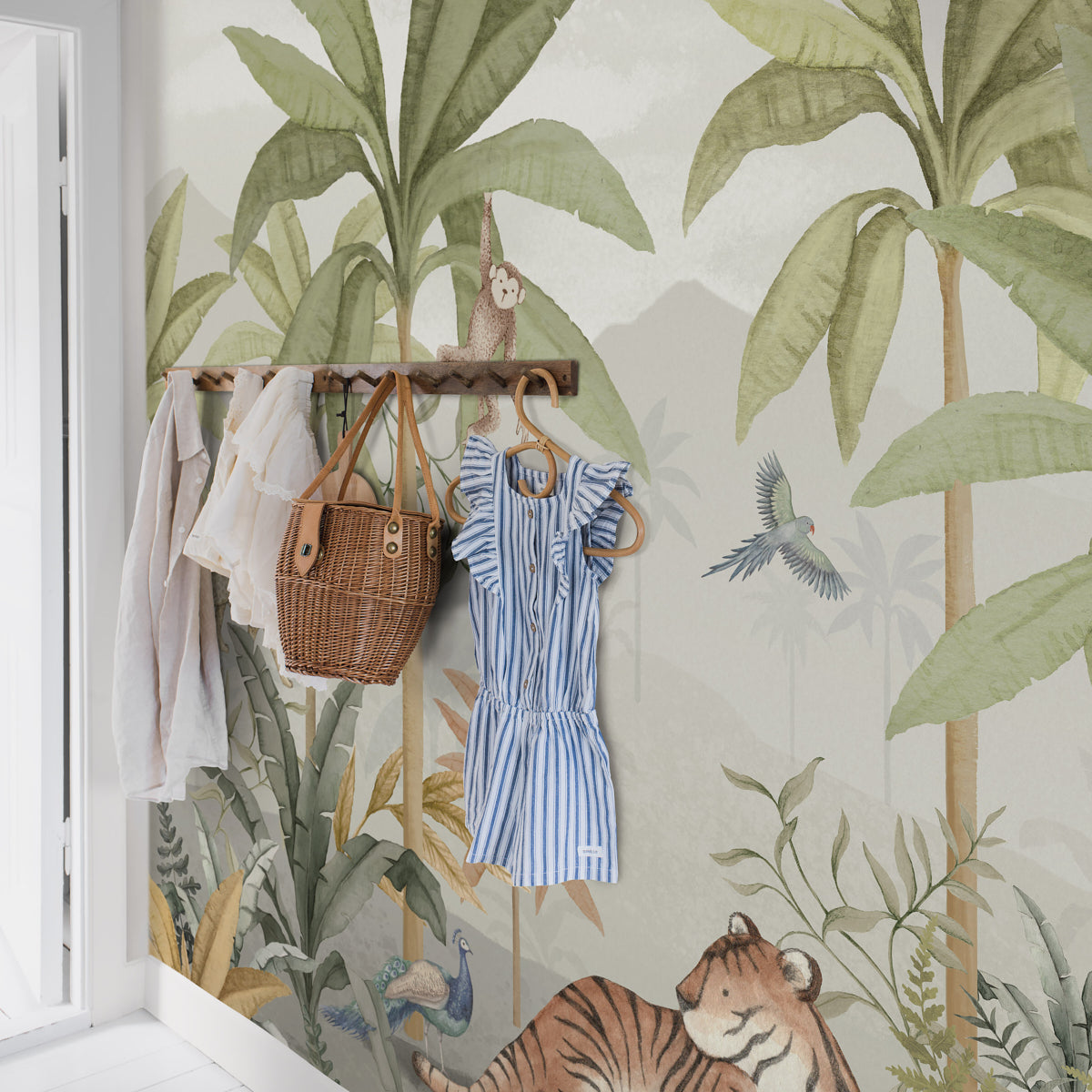Wood clothing rack with white blouse, blue striped dress, and a rattan basket against tropical jungle wallpaper.