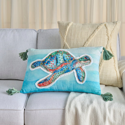Turquoise rectangular throw pillow with a multicolor sea turtle applique, white outline, green tassel corners, coastal decor.