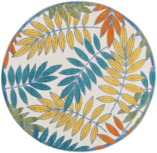 Round rug with bright yellow, teal, blue, orange, and green tropical leaf pattern on white; modern botanical rug for living room.