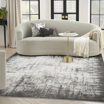 Curved beige fabric sofa with metallic-pattern and striped pillows, cream throw, gold pedestal table, on a gray rug.