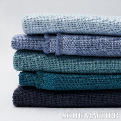 Stack of five folded terry cloth towels in gradient blues from light sky to navy, plush texture.