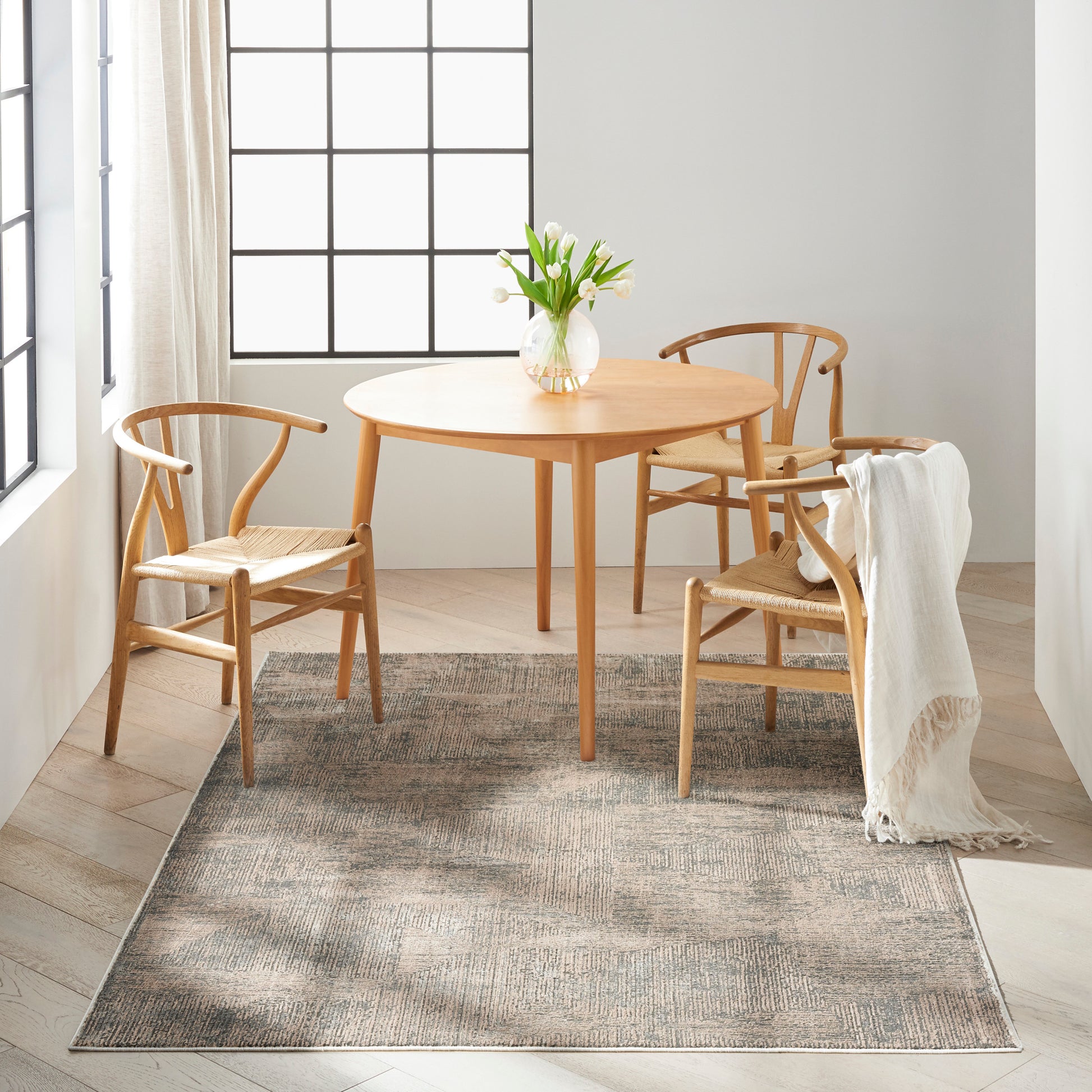 Modern neutral rug 5' x 7' in a bright dining nook, with a light wood dining table and curved-back chairs.