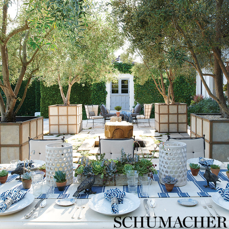 Outdoor garden dining setup with blue-and-white striped runner, succulent centerpiece, white plates, glassware, and cushioned seating.