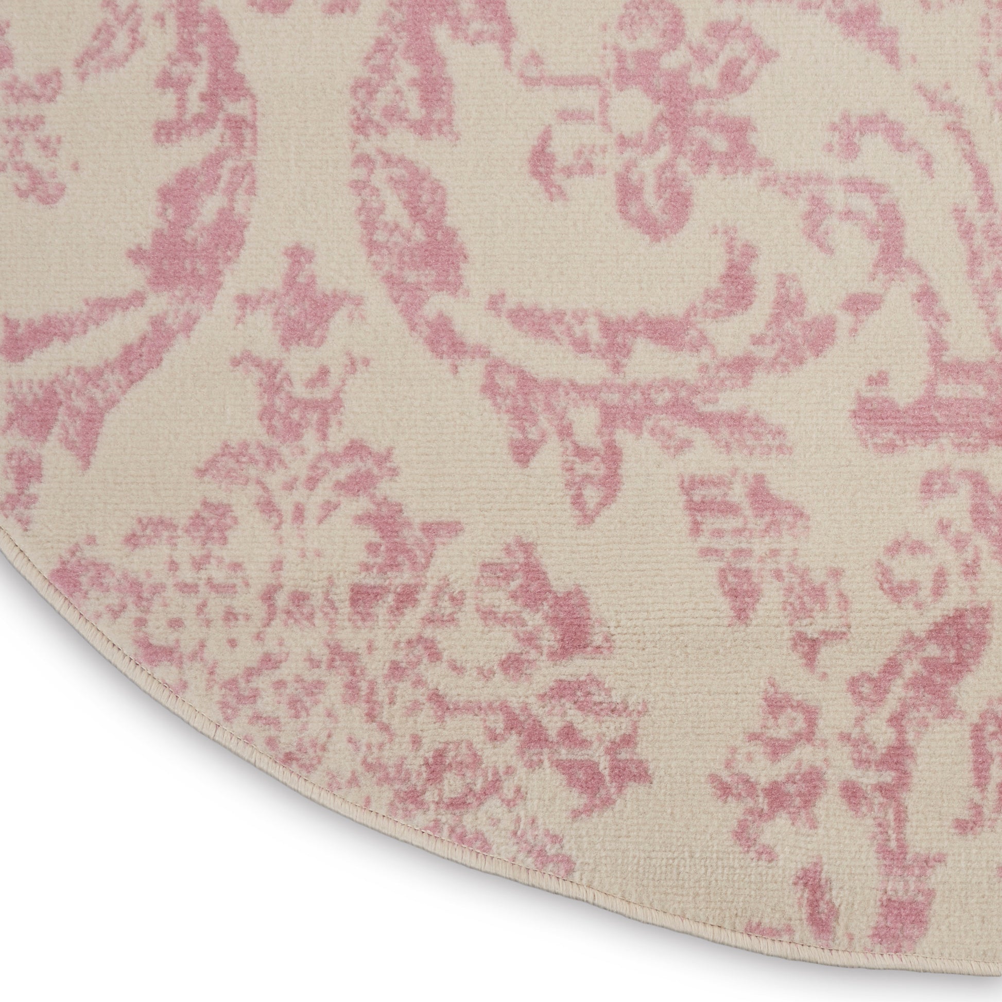Round rug in cream with pink damask pattern; soft, textured fabric for elegant living spaces.