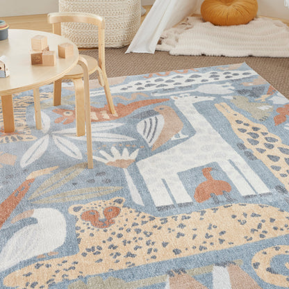Pastel patchwork area rug in blue, beige and ivory with abstract shapes; wooden kid table and chairs nearby.