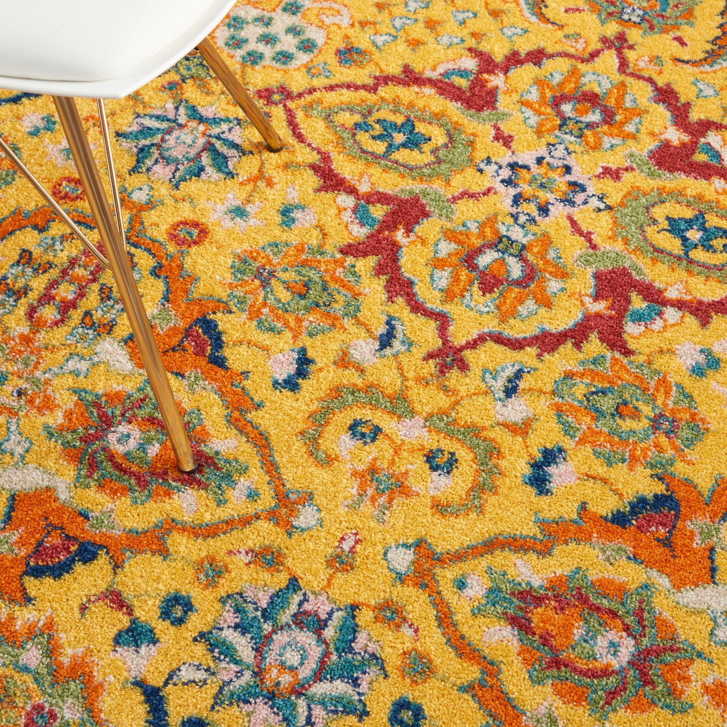 Bright yellow oriental area rug with red, blue, teal floral motifs; white chair with wooden legs partially visible.