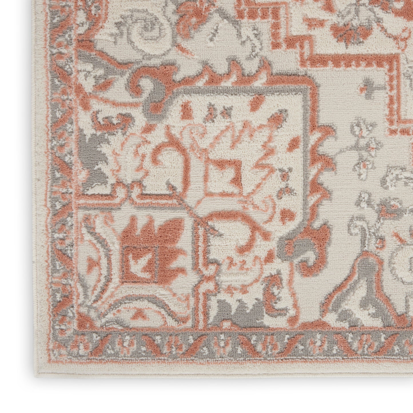 Close-up of an ornate oriental rug with ivory base, peach and gray floral-scroll motifs and a decorative border.
